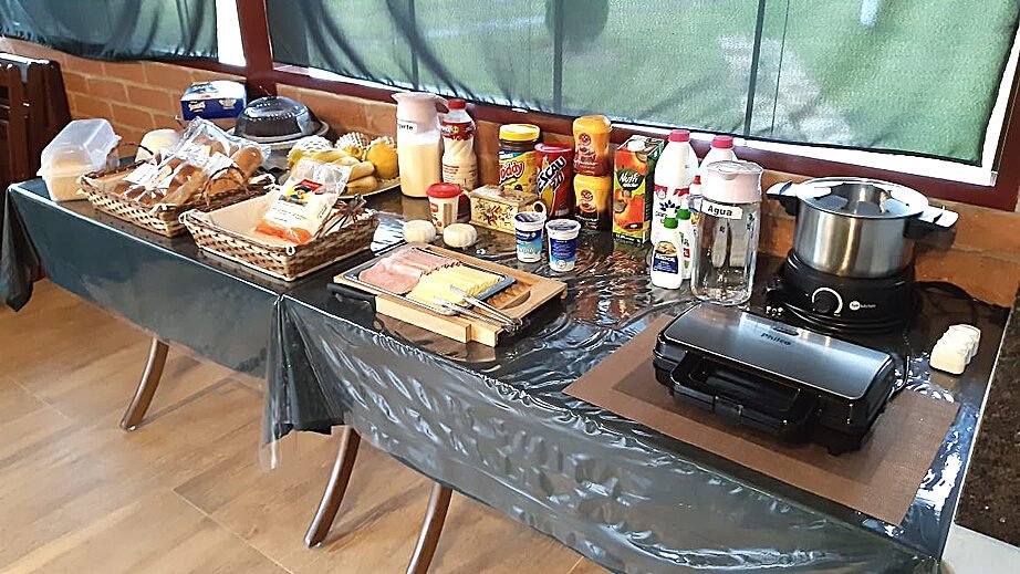 Mesa de café da manhã com pães, frios, frutas e bebidas