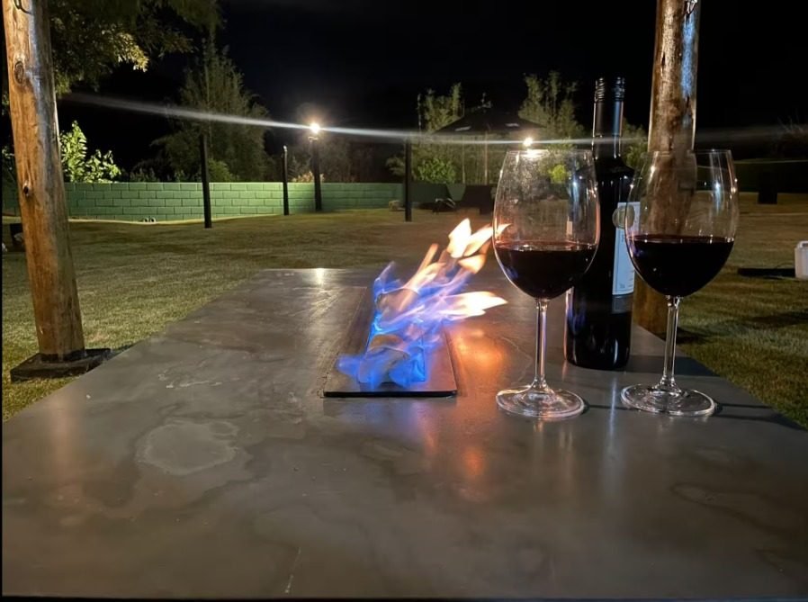 Mesa com lareira ecológica acesa e duas taças de vinho